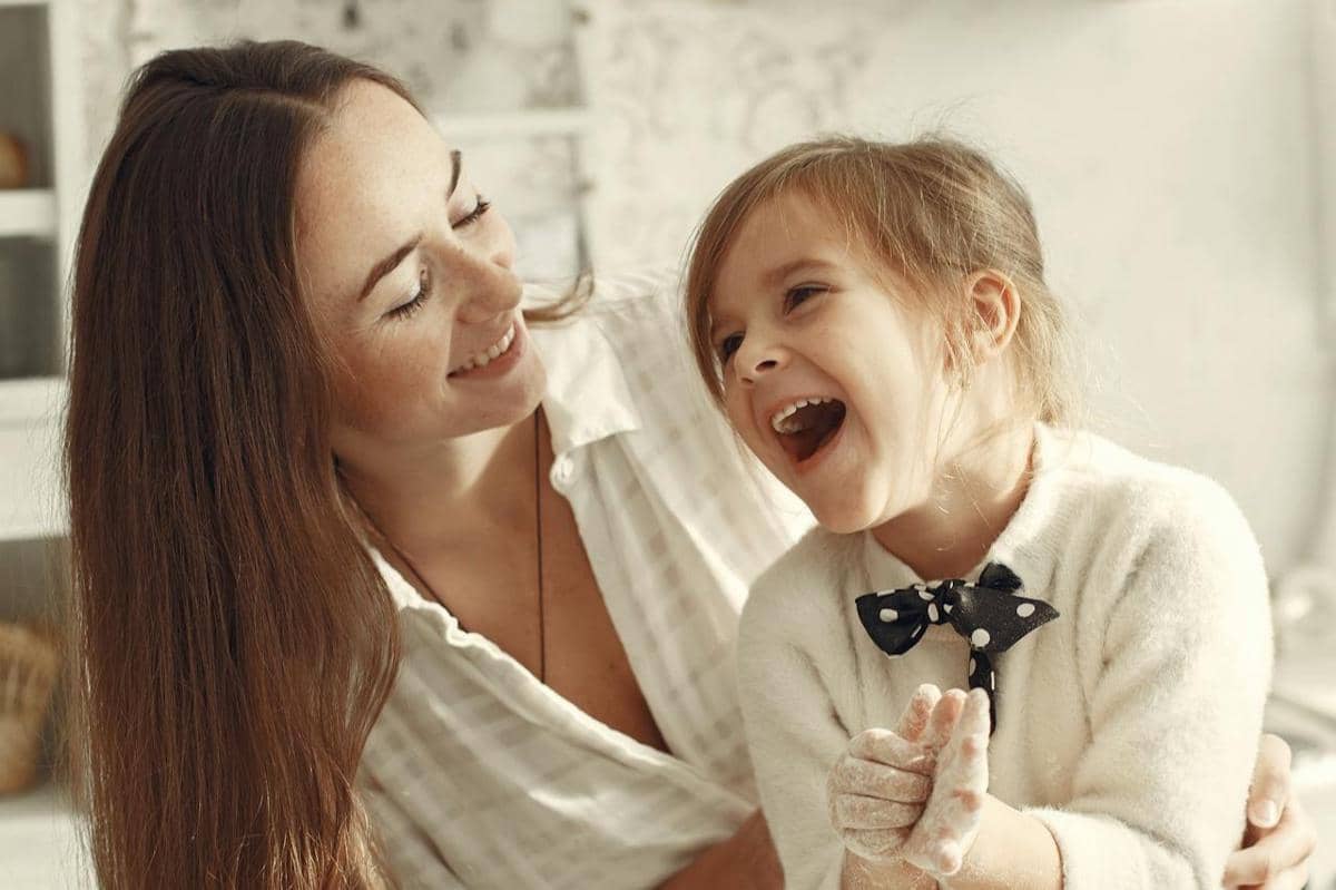 Seorang ibu sedang menemani anak perempuannya bermain.