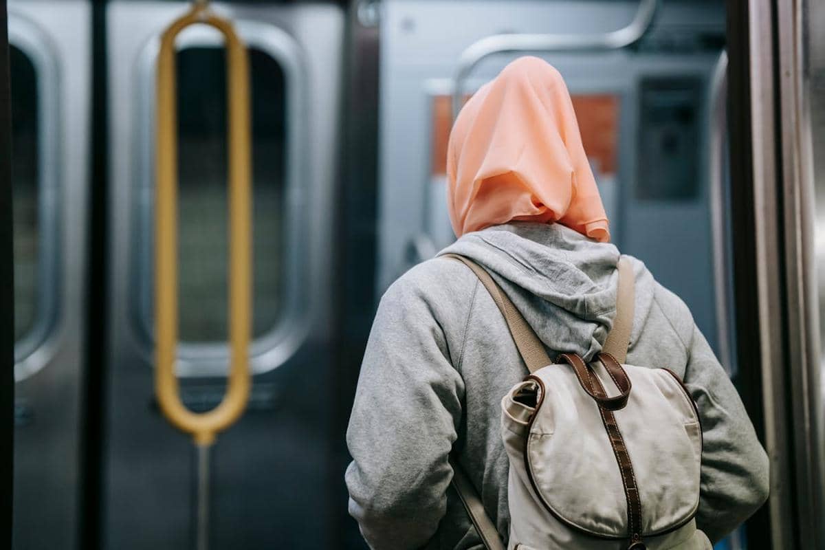 ilustrasi wanita berhijab dengan ransel di kereta bawah tanah