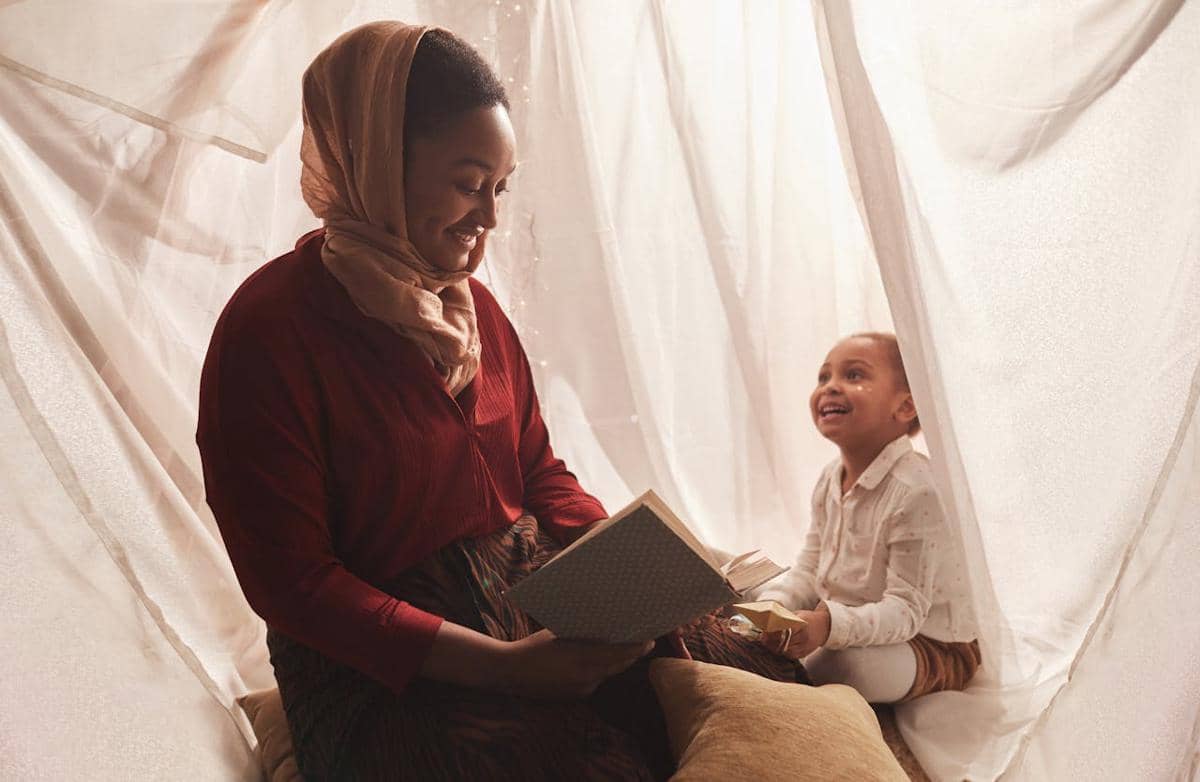Seorang ibu dan anak perempuan duduk bersama di dalam tenda, menggambarkan momen hangat kebersamaan keluarga.