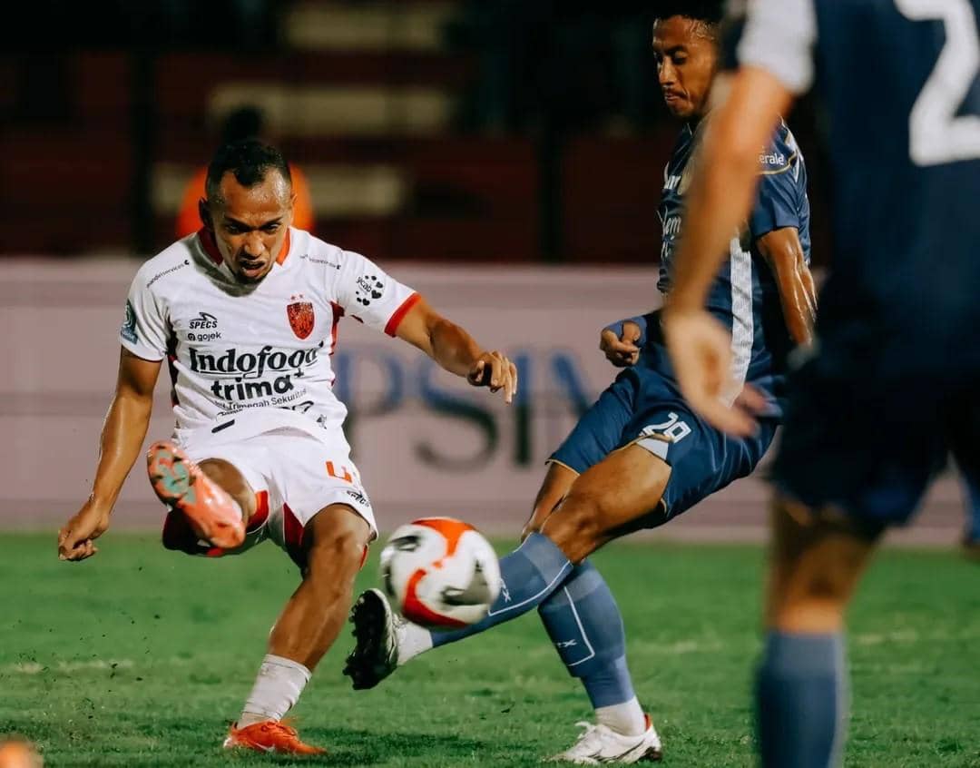 Irfan Jaya (putih) dihadang pemain PSIM Yogyakarta.