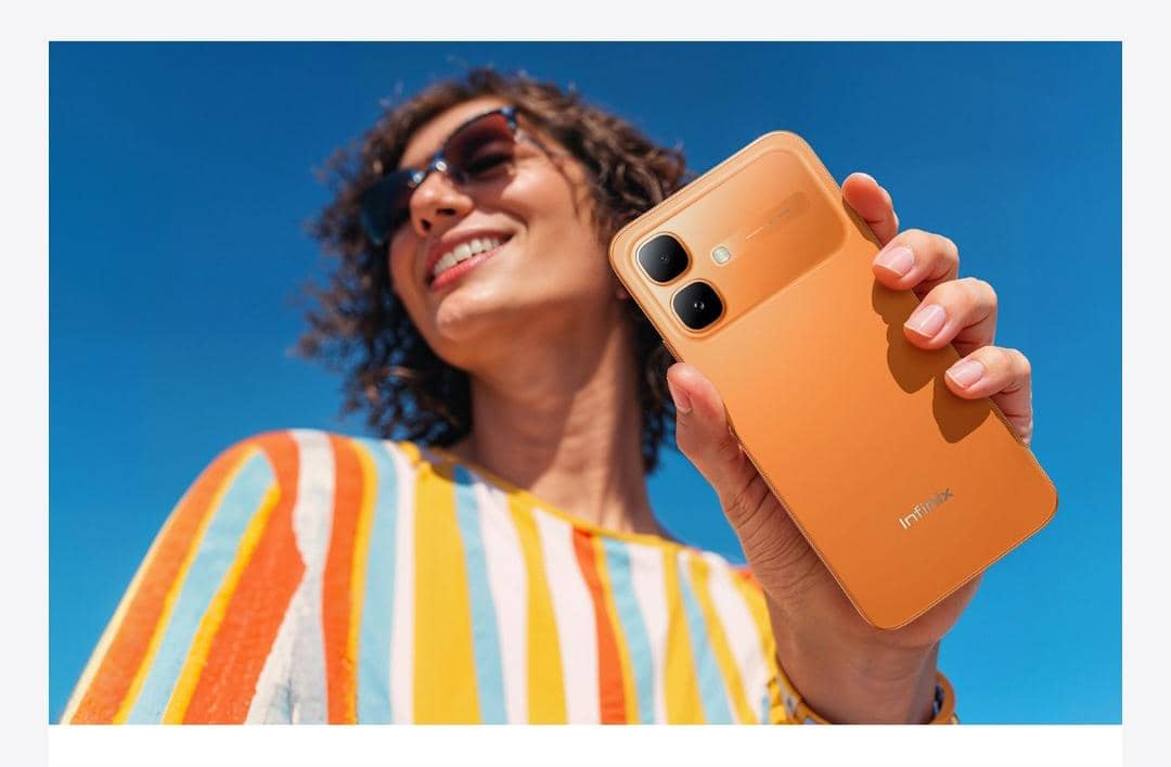 Seseorang memegang Infinix Smart 20 warna sunlike orange.