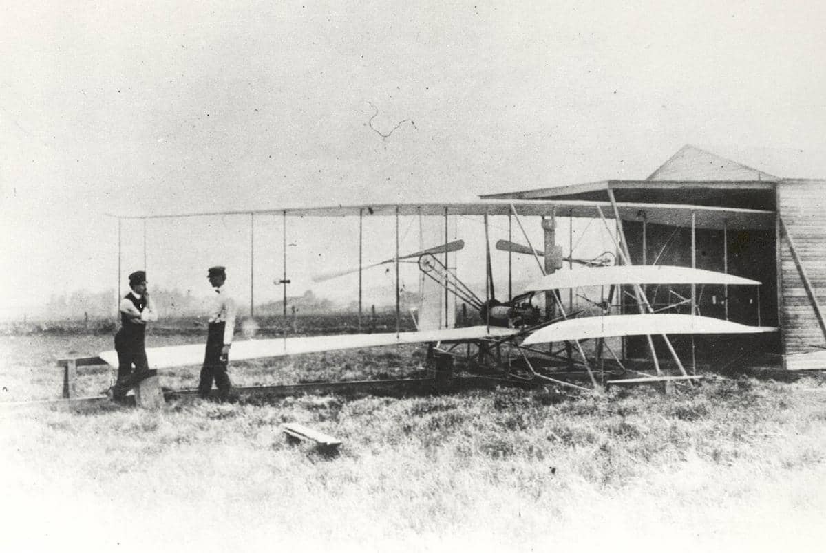 potret Wilbur dan Orville Wright berdiri di samping pesawat Flyer II
