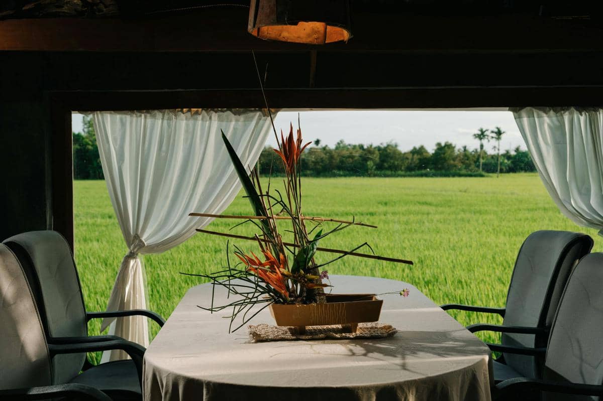 Ilustrasi area makan outdoor dengan panorama sawah luas dan suasana pedesaan yang tenang di Karangploso.