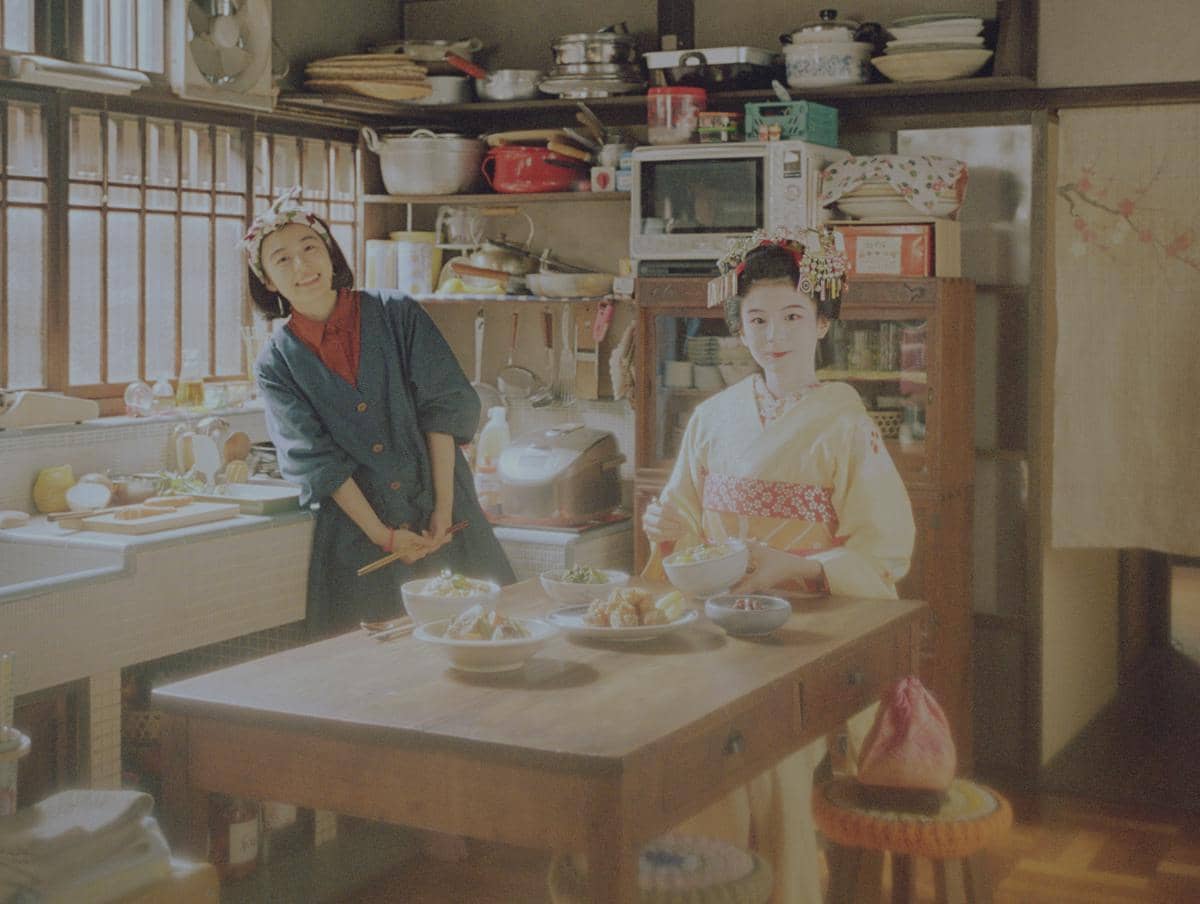 Kiyo dan Sumire dari The Makanai: Cooking for the Maiko House berdiri di dapur tradisional Jepang.