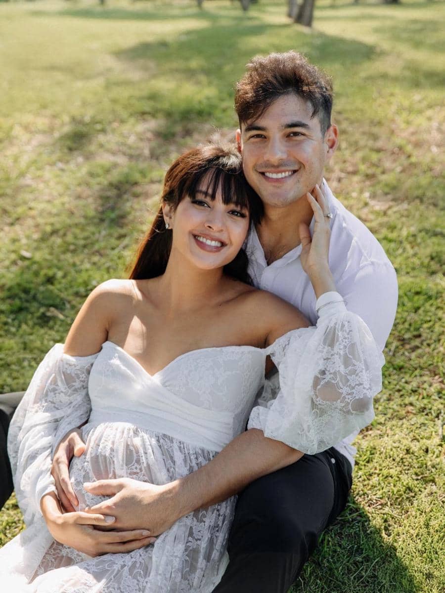 Aurelie Moeremans dan Tyler Bigenho sedang duduk di hamparan rumput, menunjukkan perut hamil Aurelie yang sudah membesar