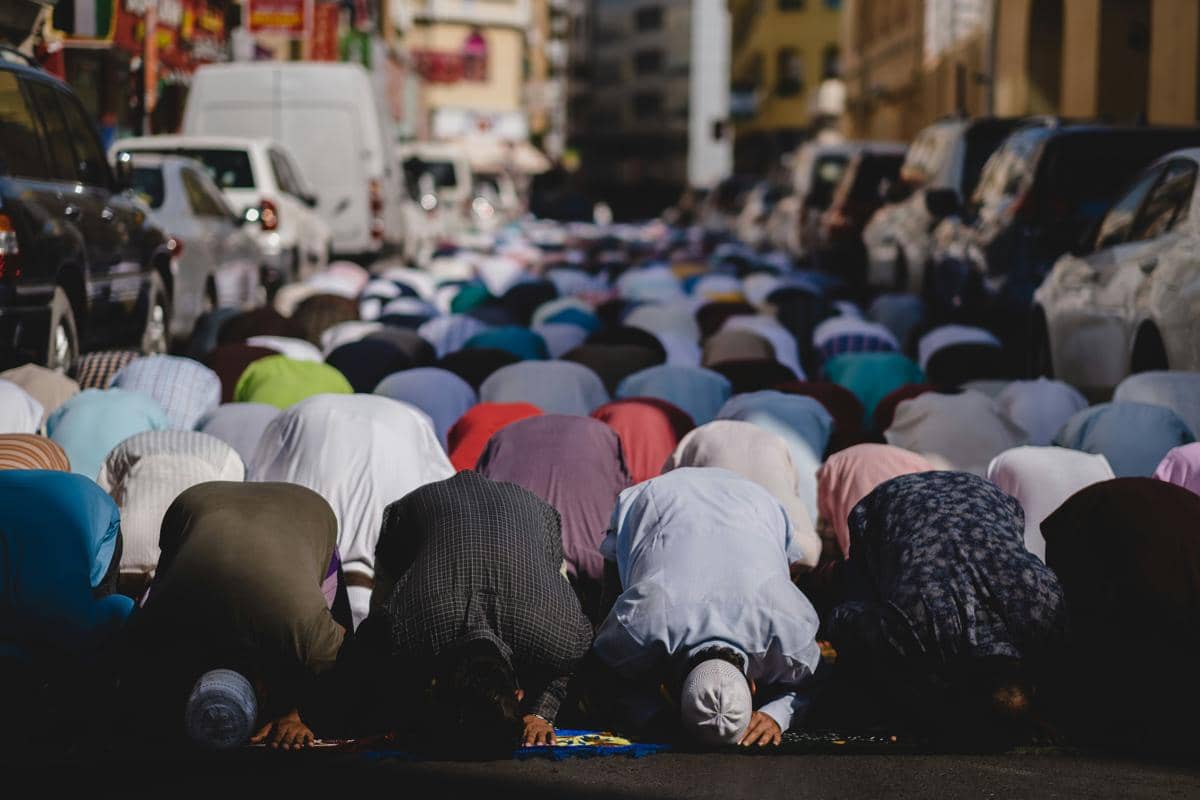 people kneeling and praying during daytime Muslims praying on Friday in Dubai. The congregation has spilled onto the road outside of the mosque.