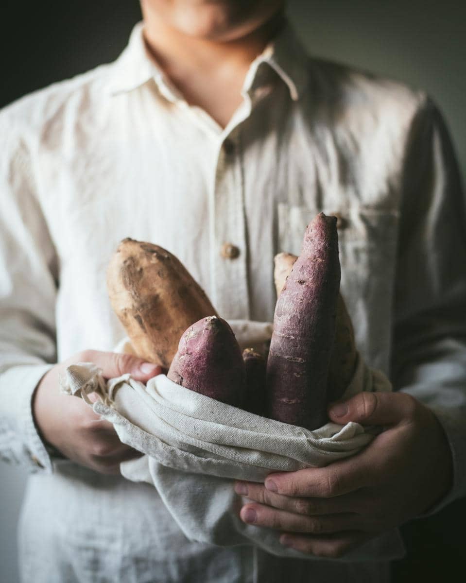 man holding a basket filled with different types of vegetables