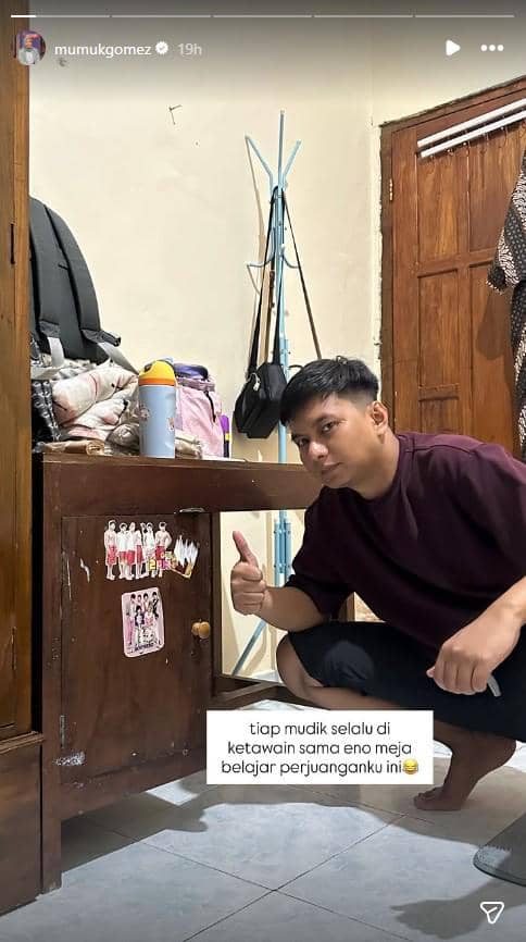 Suami Mumuk Gomez berpose di depan meja belajar lawas milik Mumuk ketika masih sekolah