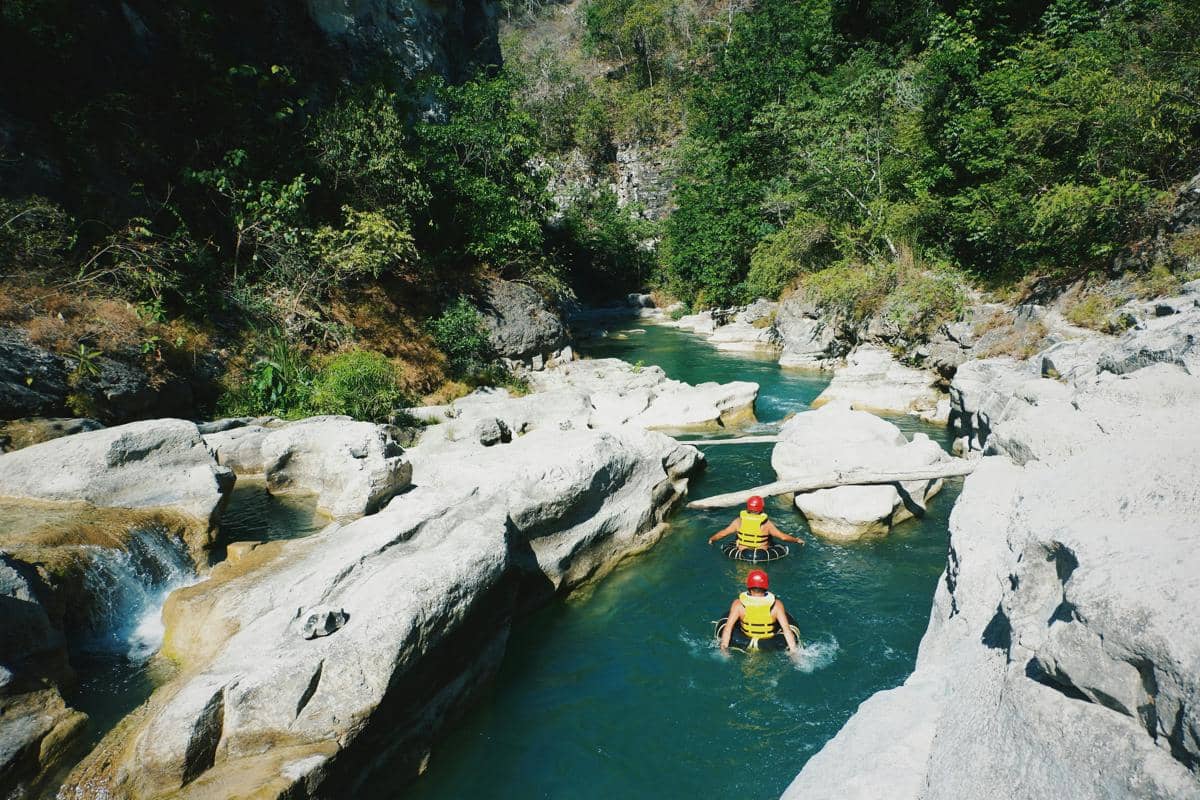 Ilustrasi aktivitas di aliran sungai jernih dengan bebatuan alami di kawasan wisata Putri Maron.