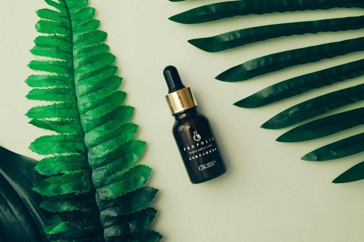 Produk skincare diletakkan dengan latar belakang dedaunan hijau alami.