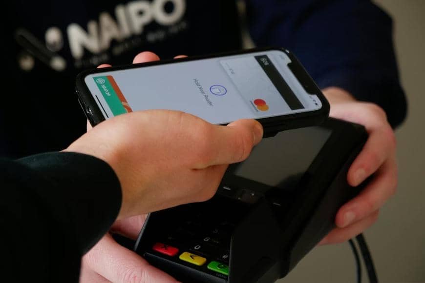 Seseorang melakukan pembayaran cashless dengan menempelkan smartphone ke mesin EDC.