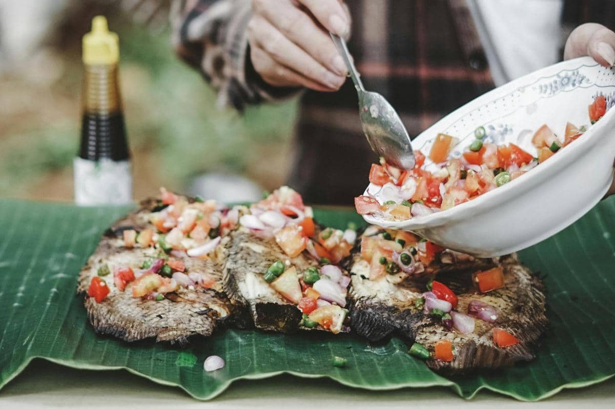 Ilustrasi ikan bakar dengan sambal pedas dan lalapan segar khas Pantura.