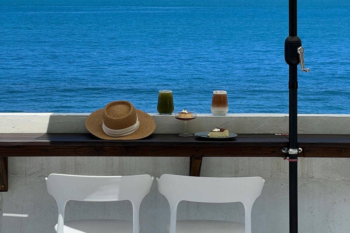 Ilustrasi kopi dan camilan ringan dengan view laut yang tenang di Pasir Putih.