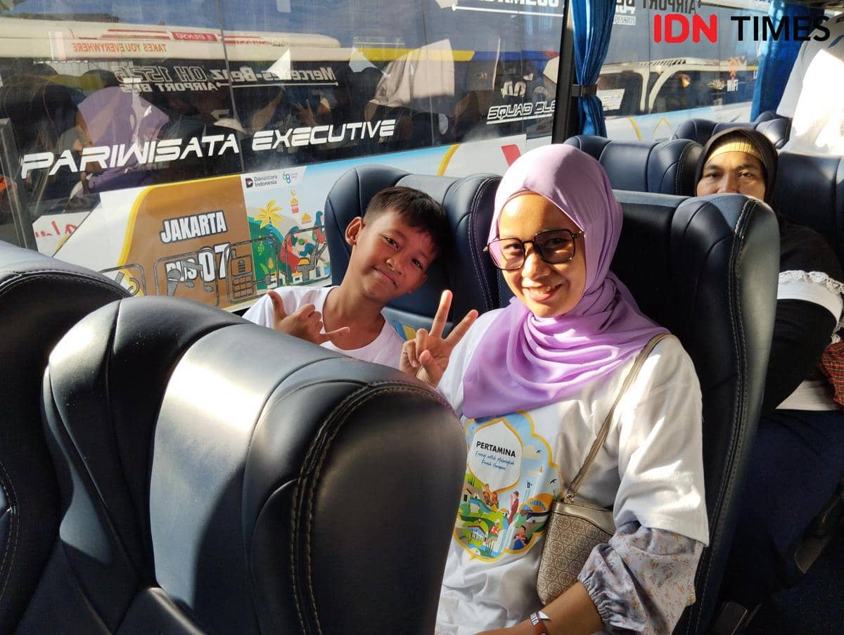 Perantau asal Pati Novian Indriani (kanan) bersama anaknya di bus untuk perjalanan ke Jakarta saat program arus balik Pertamina di Semarang, Sabtu (28/3/2026). (IDN Times/Dhana Kencana)