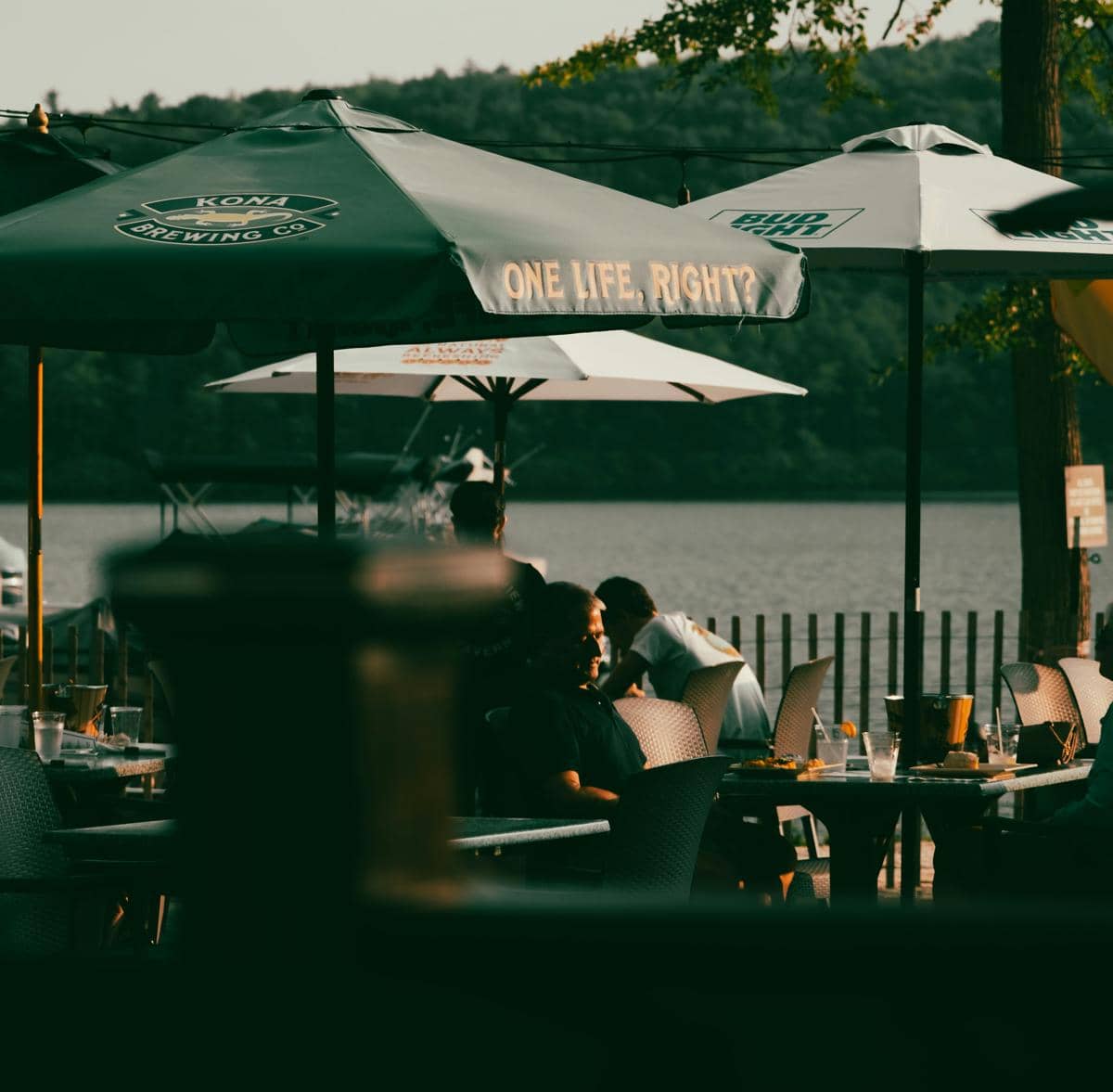 a group of people sitting at tables under umbrellas