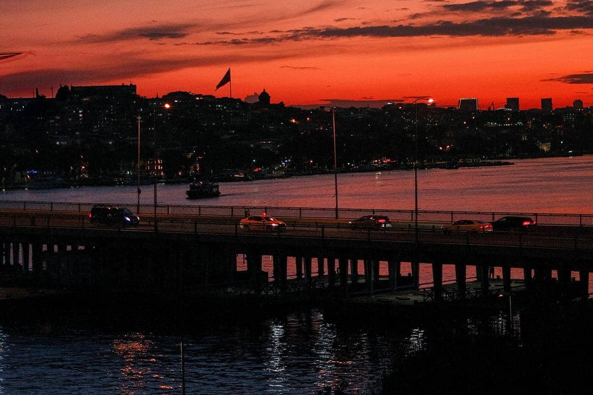 Ilustrasi pemandangan Jembatan Suroboyo saat senja dengan latar laut Kenjeran.