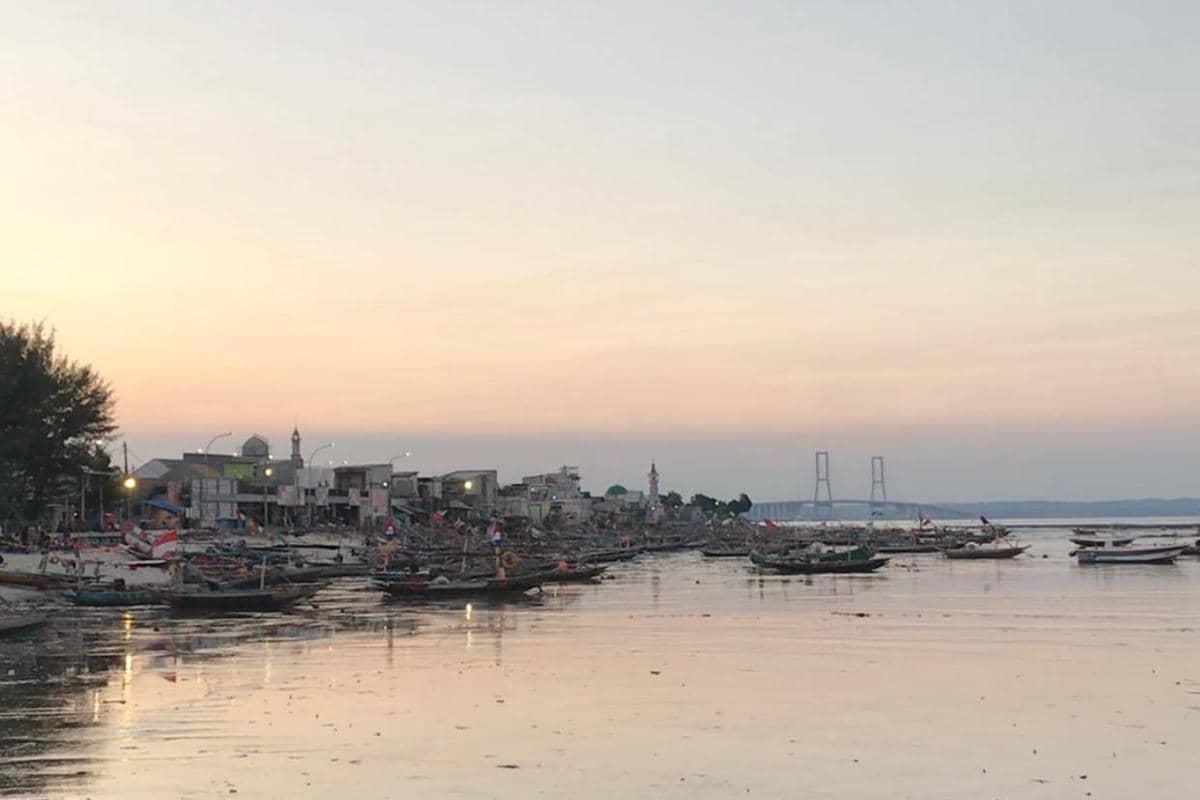 Foto Kampung Nelayan Kenjeran saat senja dengan deretan perahu nelayan.