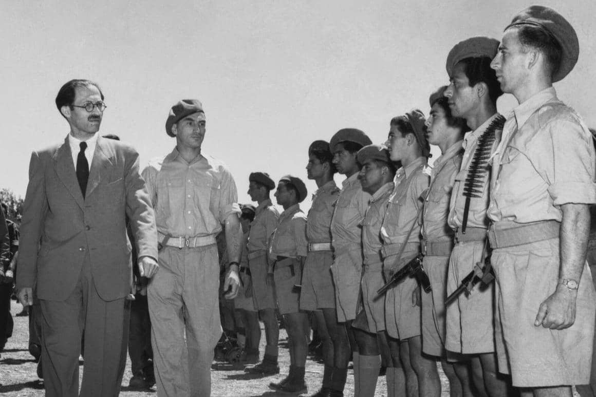Menachem Begin (1913—1992) memeriksa anggota Irgun Zvai Leumi, sebuah organisasi paramiliter Yahudi, selama parade di Yerusalem, pada 12 Agustus 1948.