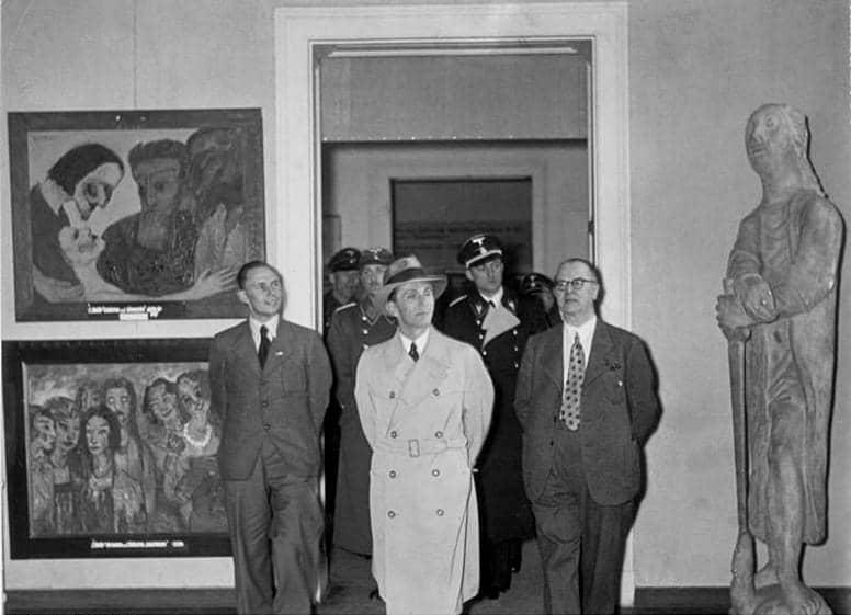Sebuah adegan dari pameran "Seni Degeneratif" yang diselenggarakan oleh Nazi di Munich pada tahun 1937, di mana para pejabat tinggi Nazi, termasuk menteri propaganda Joseph Goebbels, sedang memeriksa karya seni modernis yang disita.