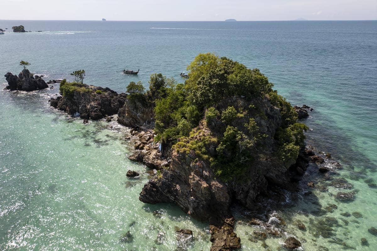 Ilustrasi Pantai Teluk Asmara dengan kumpulan pulau karang di tengah laut.