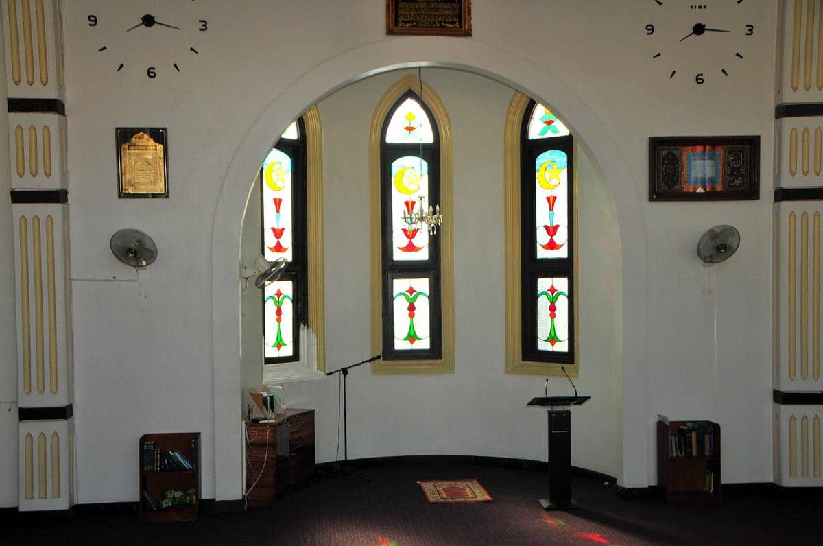 Mihrab di dalam Masjid Keizerstraat dengan hiasan kaligrafi dan ornamen bernuansa hijau serta emas yang mencolok.