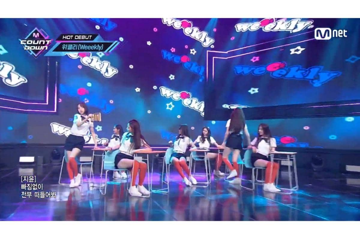 penampilan debut Weeekly dengan properti meja dan kursi kelas