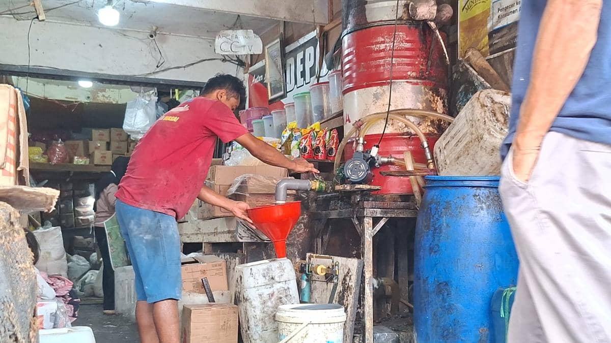 Seorang karyawan menuangkan minyak curah ke dalam sebuah wadah