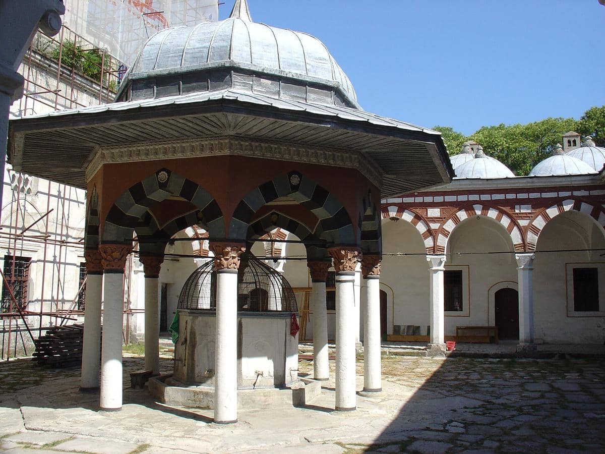 Pelataran interior Masjid Tombul dengan dinding batu, lengkungan pintu, dan area terbuka di bawah langit cerah.