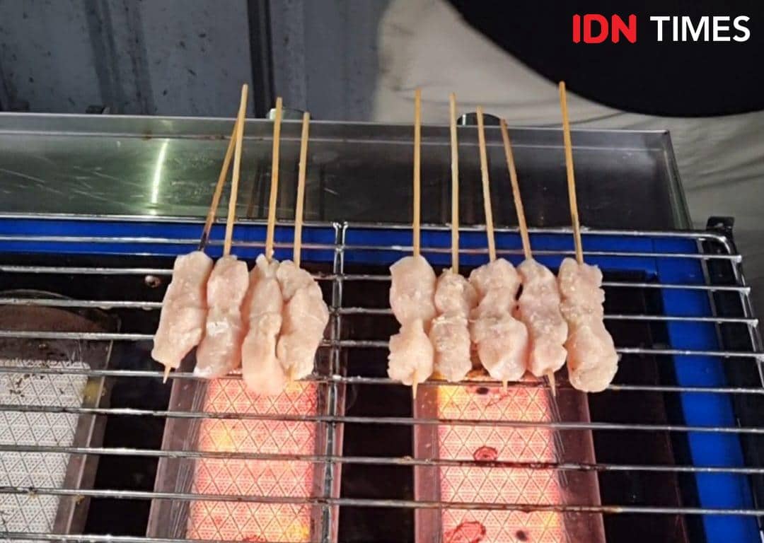 Beberapa tusuk sate ayam sedang dibakar di atas panggangan dengan bara api menyala di sebuah usaha kecil di Palembang.