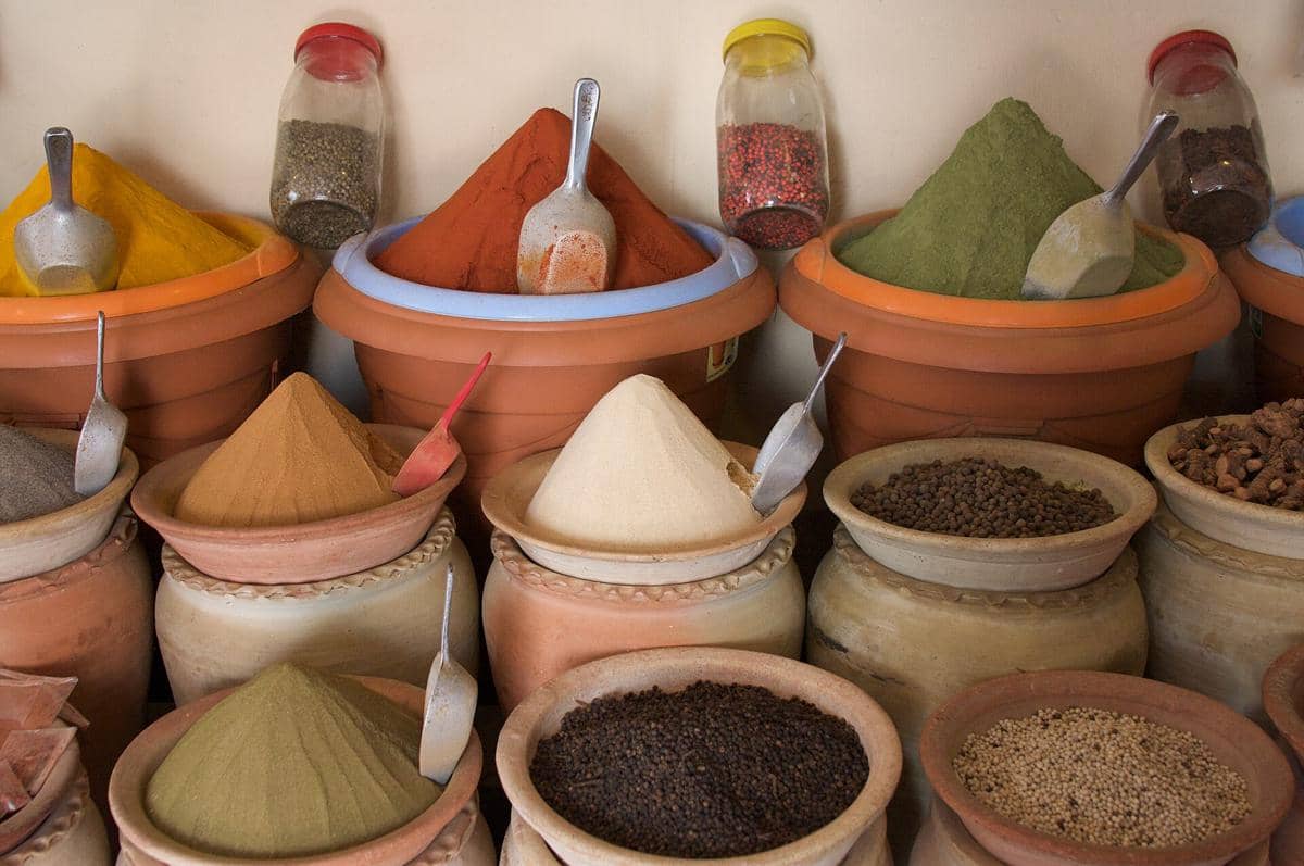 Tumpukan berbagai rempah warna-warni seperti kunyit, paprika, dan lada dalam wadah tanah liat di pasar Houmt-Souk.