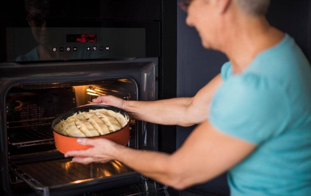 Ilustrasi proses memanggang kue dengan adonan, peralatan dapur, dan oven di area kerja rumah yang rapi.