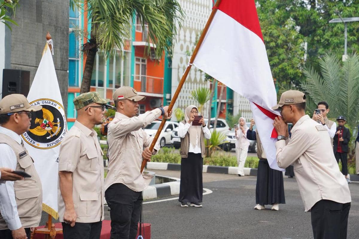 Petugas Penyelenggara Ibadah Haji (PPIH) mengecup bendera Merah Putih sebagai tanda pengabdian kepada negara Jumat (17/04/2026) (Dok. Media Center Haji)