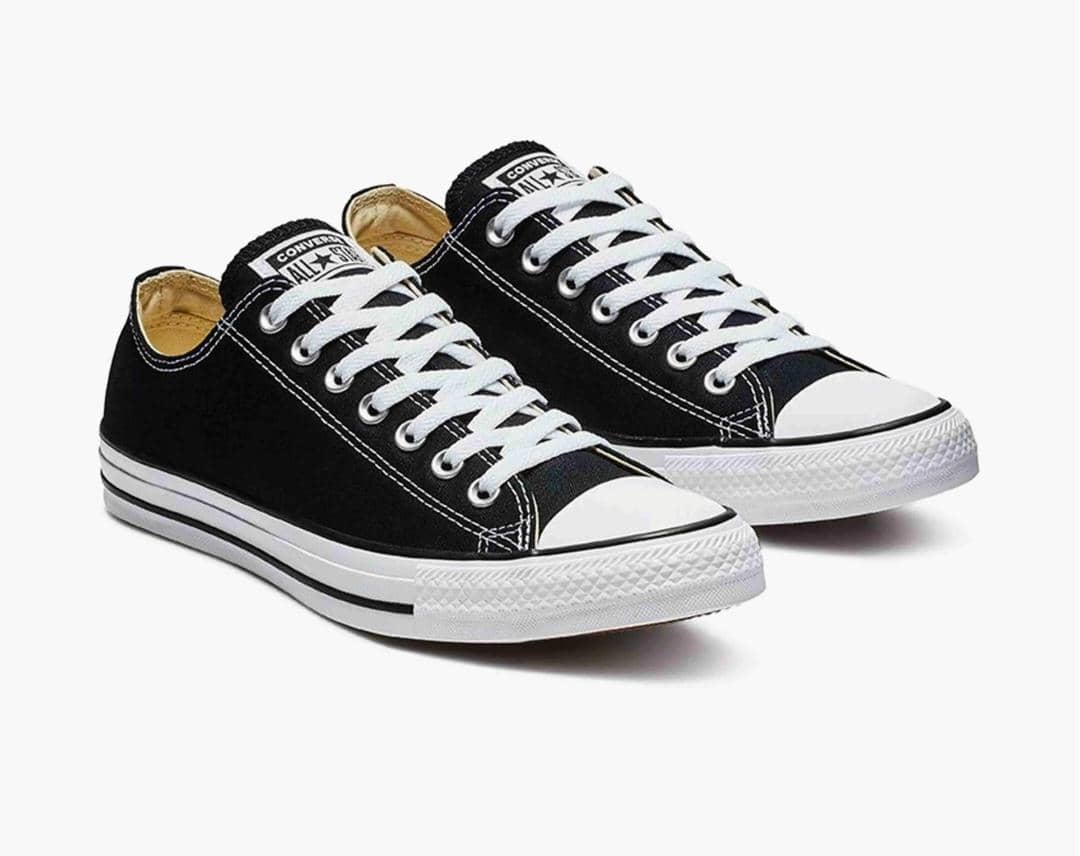 Sepasang sepatu kanvas hitam model low-cut dengan sol karet putih dan tali sepatu putih bergaya klasik.