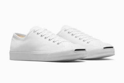 Sepasang sepatu kanvas putih model low-cut dengan sol karet putih dan detail garis hitam di ujung depan.