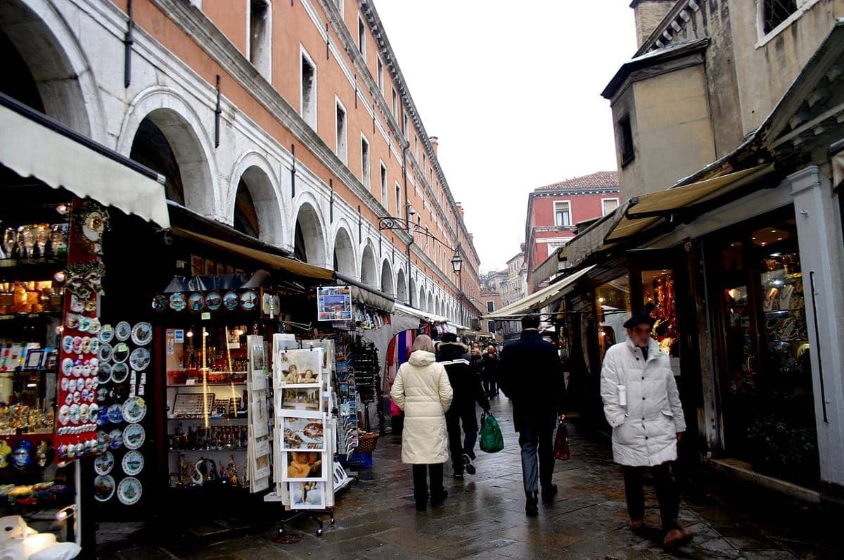 Para turis berjalan di sepanjang jalan perbelanjaan Ruga dei Oresi yang ramai di dekat Jembatan Rialto di Venesia, Italia. 