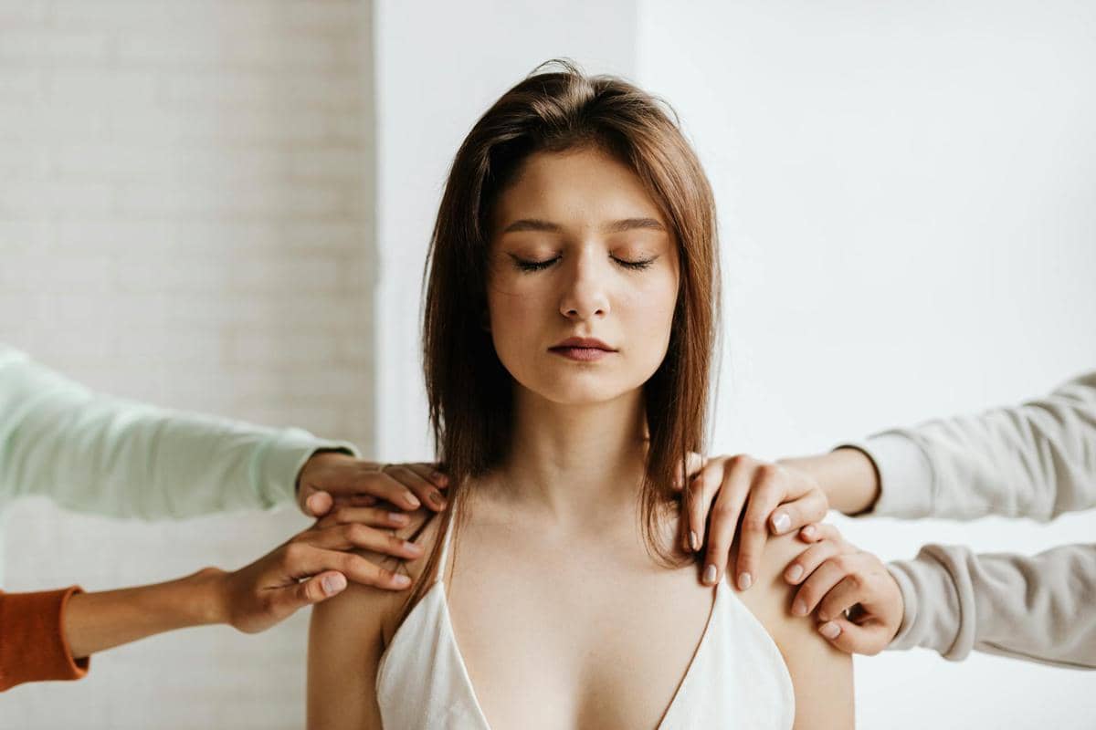 beberapa tangan yang memegang pundak seorang wanita 