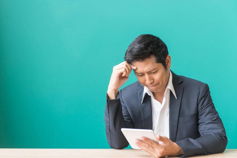 karyawan baru sedang memegang kepala sambil melihat tablet