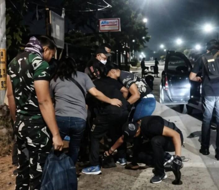 Petugas gabungan menangkap seorang pelaku begal di kawasan Belawan pada malam hari di tepi jalan dekat kendaraan yang terparkir.