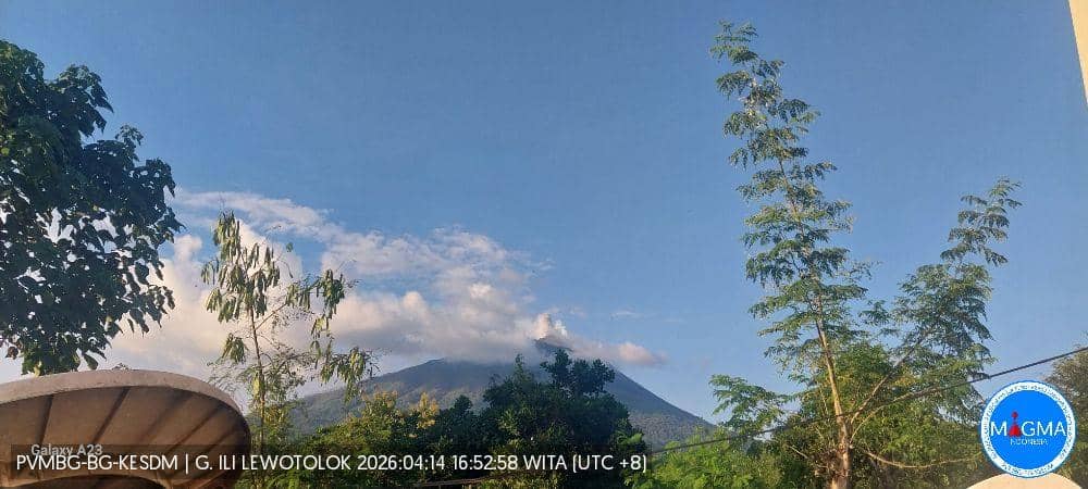 Gunung Ile Lewotolok terlihat dari kejauhan dengan puncak sebagian tertutup awan di bawah langit cerah pada 14 April 2026.
