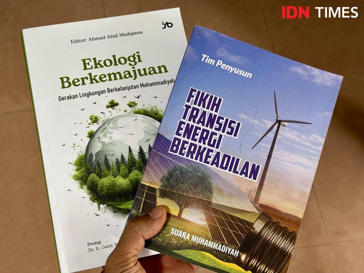 Dua buku berjudul Ekologi Berkemajuan dan Fikih Transisi Energi Berkeadilan dipegang oleh seseorang di atas permukaan berwarna cokelat.