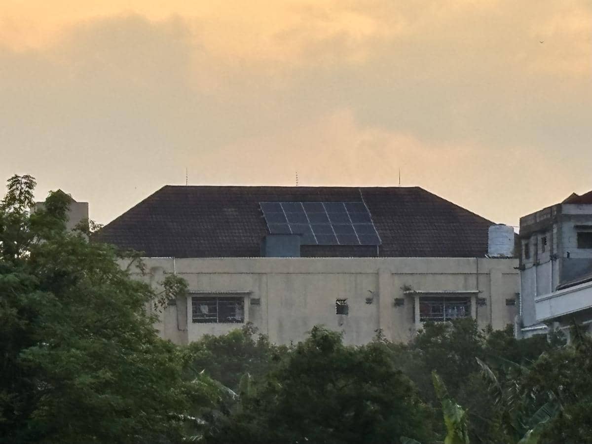 Panel surya terpasang di atap gedung asrama Pondok Pesantren Muhammadiyah Kudus dengan latar langit senja berwarna oranye.