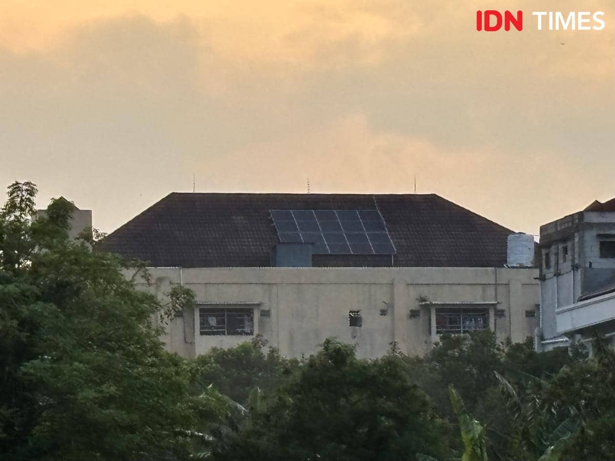 Panel surya terpasang di atap gedung asrama Pondok Pesantren Muhammadiyah Kudus dengan latar langit senja berwarna oranye.