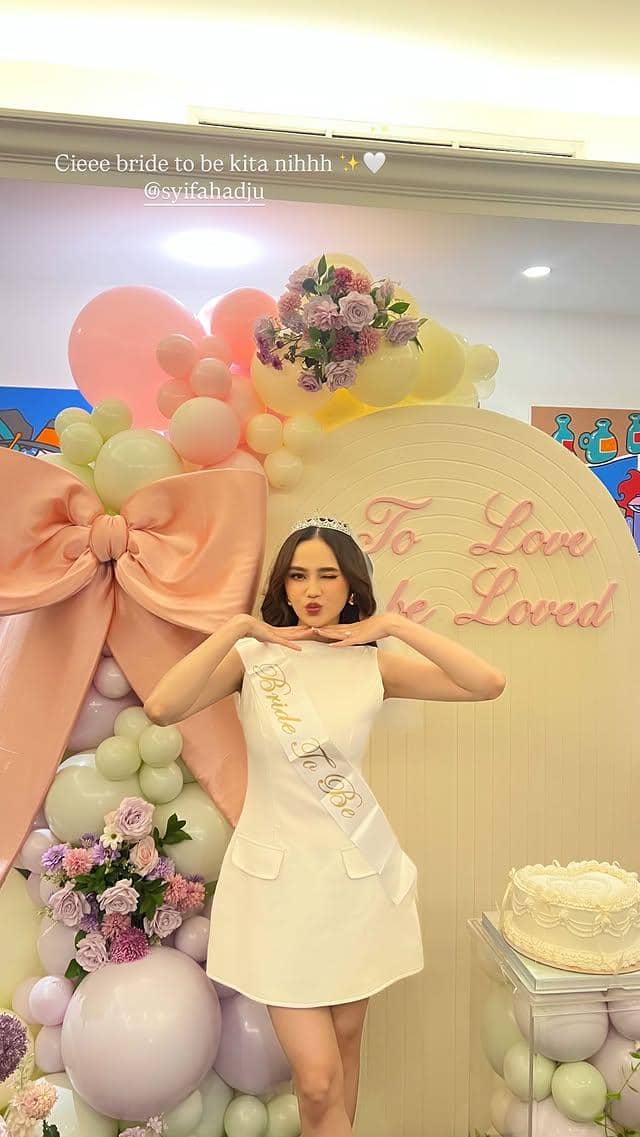 Syifa Hadju mengenakan gaun putih dan selempang bertuliskan 'Bride To Be' berpose di depan dekorasi balon pastel dan bunga