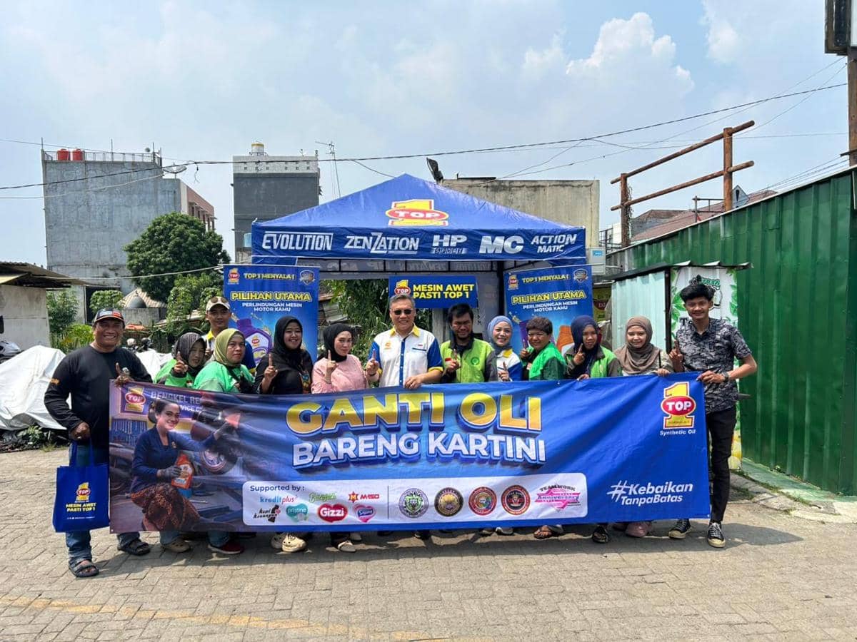 Sejumlah driver ojek online berfoto bersama di acara ganti oli gratis yang diselenggarakan oleh TOP 1 di bawah tenda biru.