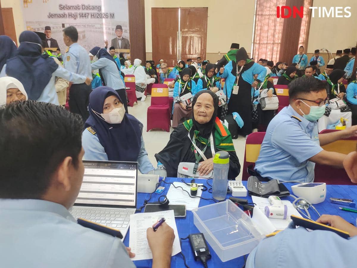 Petugas kesehatan memeriksa calon jemaah haji kloter pertama di Embarkasi Medan, dengan suasana ramai dan penuh antusiasme.