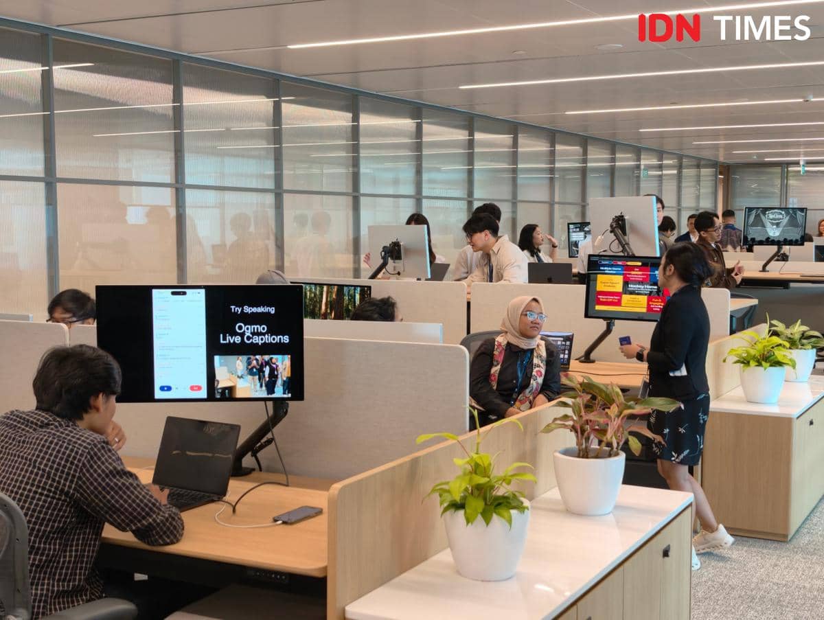 Suasana ruang kerja modern di Apple Developer Institute Jakarta dengan beberapa orang bekerja di depan komputer dan berdiskusi.