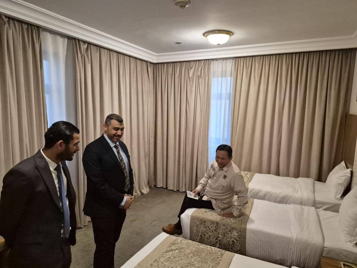 Beberapa petugas memeriksa kondisi kamar hotel dengan tempat tidur rapi dan tirai tertutup untuk memastikan kesiapan akomodasi jemaah haji.