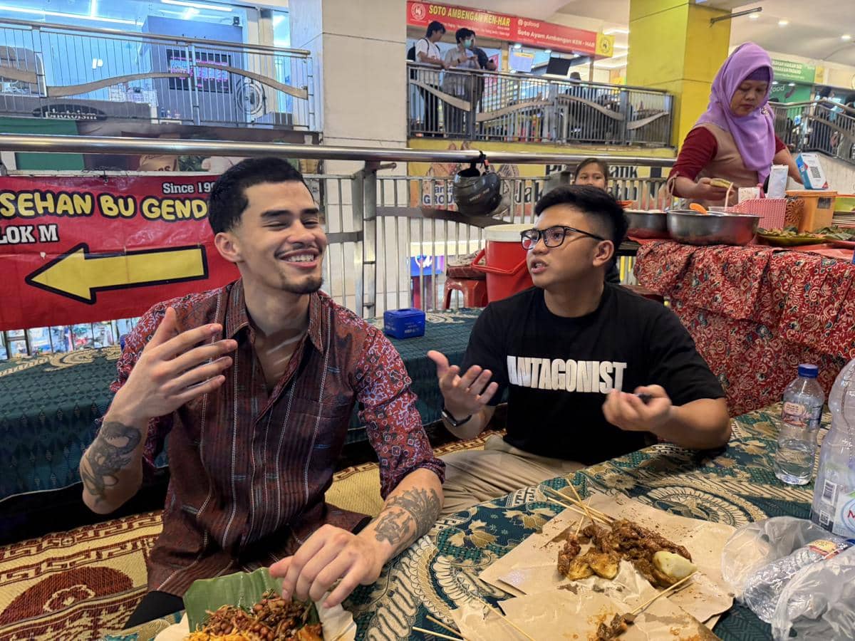 Sneako dan Bigmo duduk di warung makan tradisional di Jakarta sambil berbincang dan menikmati makanan khas Indonesia di atas daun pisang.