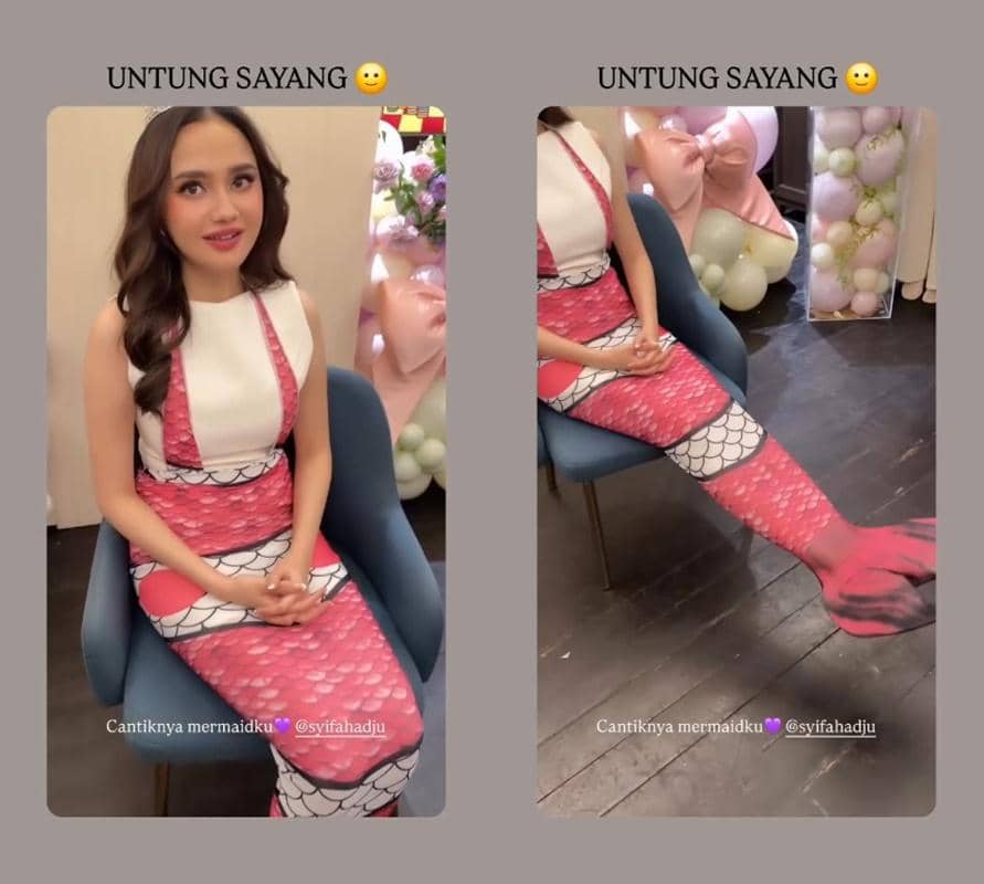 Seorang wanita duduk di kursi mengenakan kostum bertema putri duyung berwarna merah muda dan putih saat acara bridal shower dengan dekorasi balon pastel di sekitarnya.