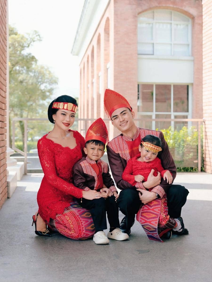 Keluarga Hanum Mega berpakaian adat berwarna merah dan cokelat berpose bersama di luar gedung bata untuk merayakan Hari Kartini 2026.